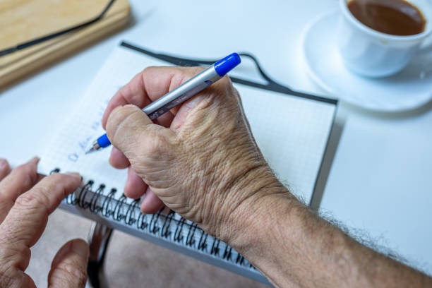 istock Old man hands writting notes while drinking coffee in living room 1700127136