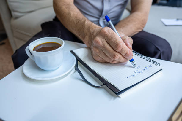 istock Old man hands writting notes while drinking coffee in living room 1700127652
