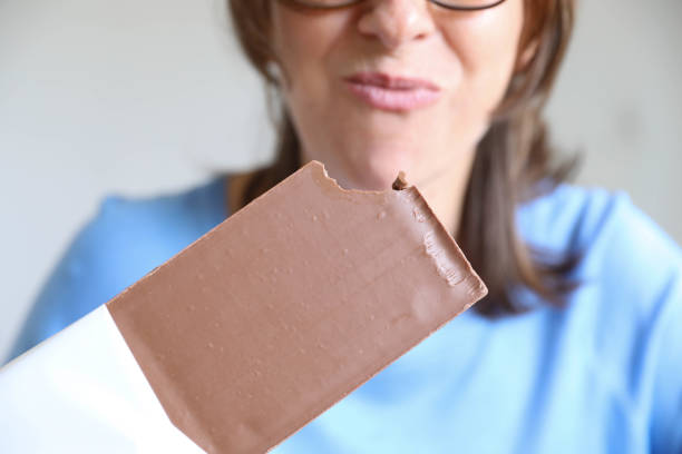 Happy mature lady eating chocolate.