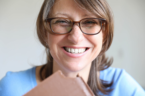 Happy mature lady eating chocolate.