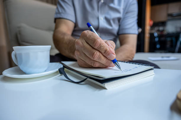 istock Old man hands writting notes while drinking coffee in living room 1700127801