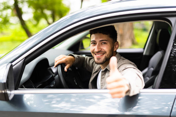 istock Young man smiling happy doing ok sign driving car. 1700139412