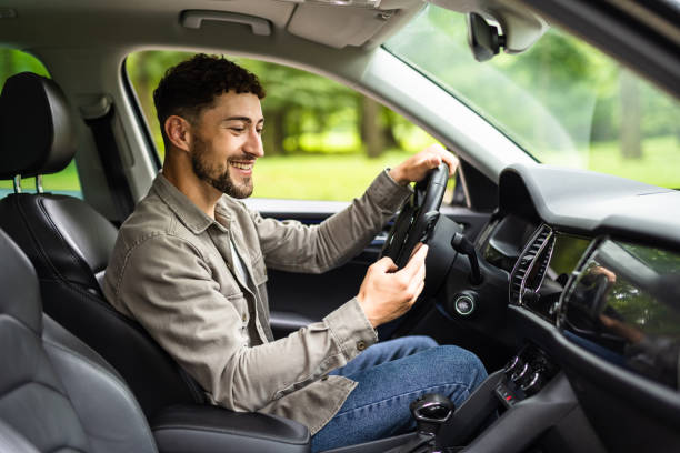 istock A young man driving his own car uses a smartphone or phone. Multitasking concept 1700145063