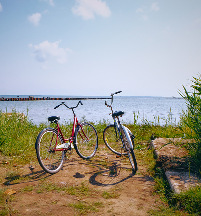 Two retro bicycles for couple on the beach on background a blue Baltic sea on a sunny day. Vibrant colors, green grass and beautiful calm horizon. High quality photo