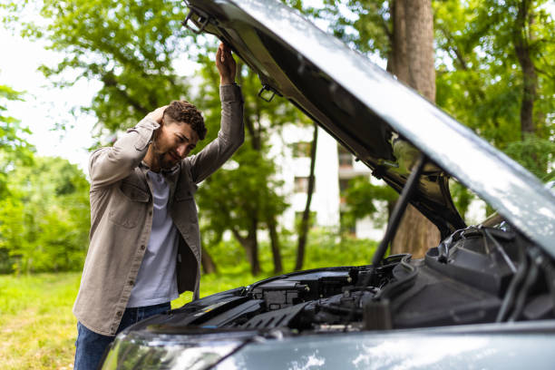 istock Man checking his broke down car on the street 1700154094