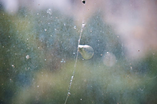 A vertical crack on a dirty glass, on a green background. Broken glass, cracks in the glass.