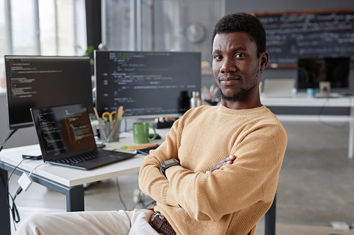 Portrait of African American programmer looking at camera while sitting in IT office
