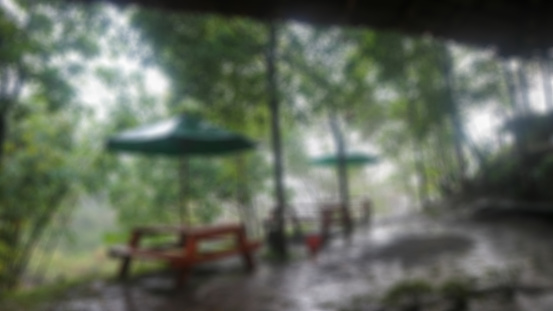 blurred Wooden table with umbrella in the rain