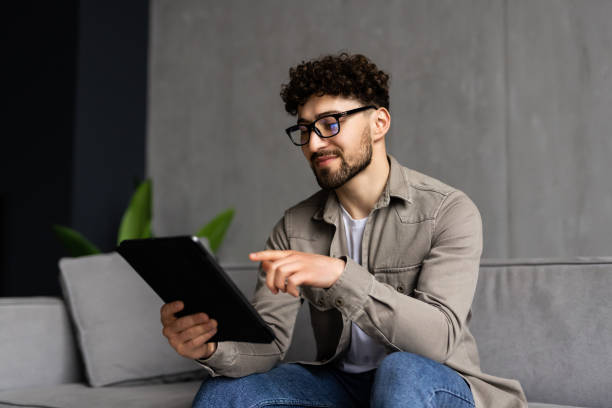 istock Young handsome man surfing on tablet on a couch 1700179778
