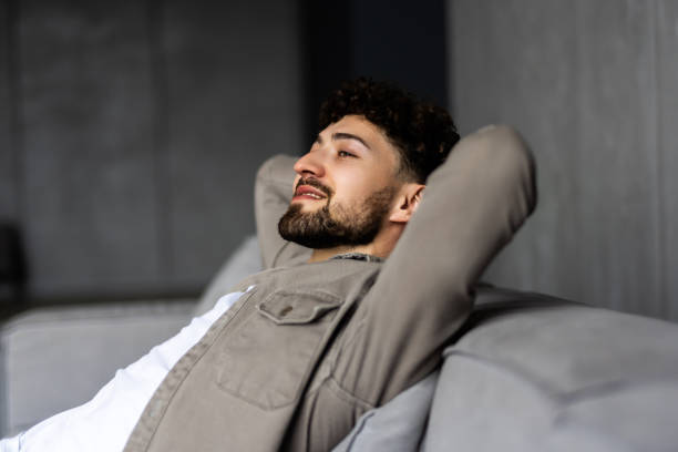 istock Young handsome man sitting on coach rest at home 1700187528