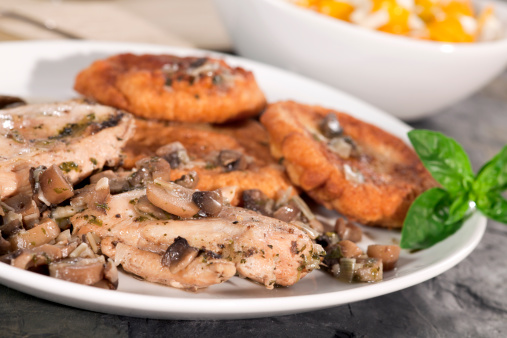 Chicken breast with mushrooms and potato pancakes. Lunch with vegetable salad. Selective focus..
