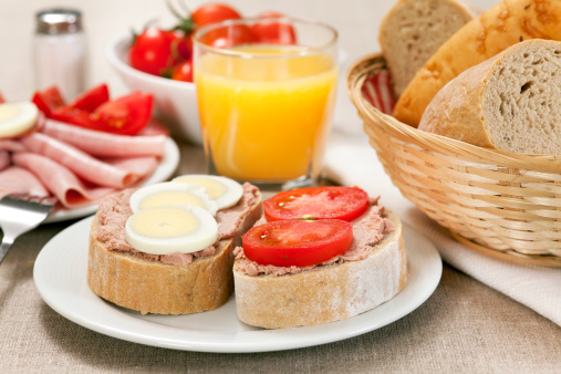 Breakfast with bread, liver pate,ham,egg,tomatoes and juice. Selective focus, shallow DOF..