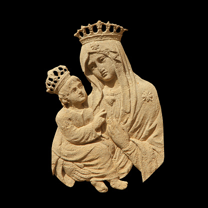 Virgin Mary with Jesus Christ. Fragment of an ancient statue isolated on black backgrouund.