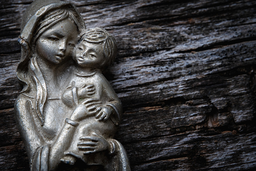 Virgin Mary with the baby Jesus Christ against wooden background. Copy space.