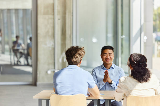 Felice agente asiatico che parla con i suoi clienti in ufficio. - foto stock