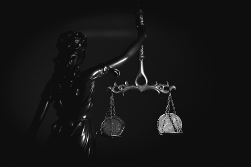 Silhouette of goddess of justice Astraea with mechanical weighing scale and with money as symbol of bribery, injustice and double standards. Selective focus.