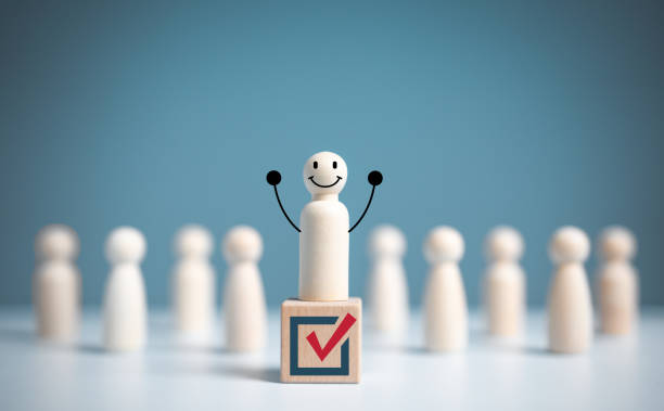 Raise hand wooden figure stands above a wooden cube with vote symbol among another. open-mindedness or public hearing, Elections concept. Volunteers, parties, candidates, constituency electorates. levante la mano de la figura de madera se encuentra sobre un cubo de madera con el símbolo del voto entre otros. apertura mental o audiencia pública, concepto de elecciones. voluntarios, partidos, candidatos, electorados de circunscripción.