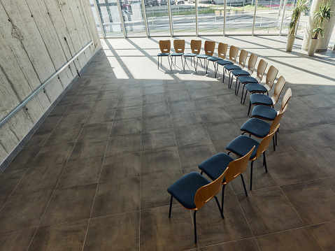 Large group of office chairs in semi-circle in a hallway of an office building. Copy space.