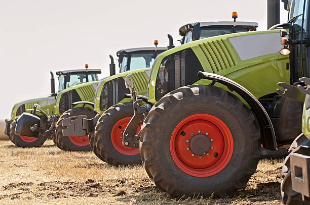New tractors on field New tractors on field in a row. Selective focus, side view. agricultural machinery stock pictures, royalty-free photos & images