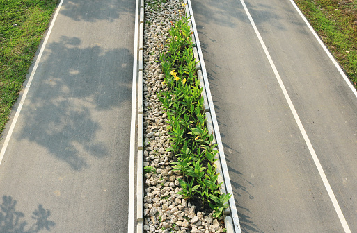 Asphalt road with garden on traffic island aerial top view.