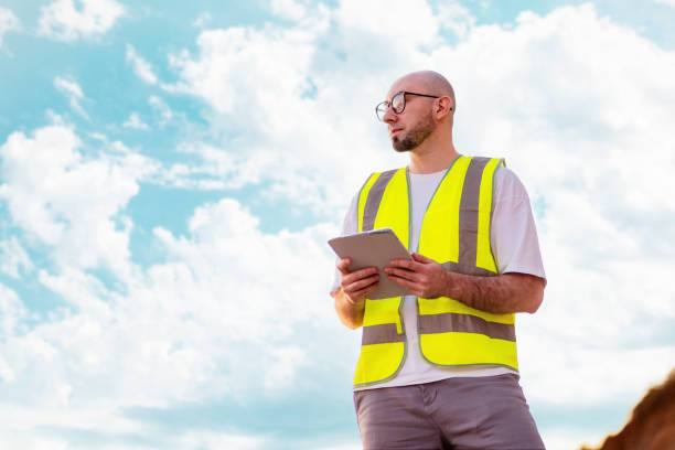 istock Clear air. Bottom view of bald bearded man with glasses holding tablet against blue cloudy sky. Copy space. Concept of environmental protection and recycling industry 1700242551