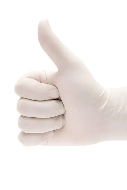 Hand in surgical gloves giving thumbs up. Isolated on a white background.