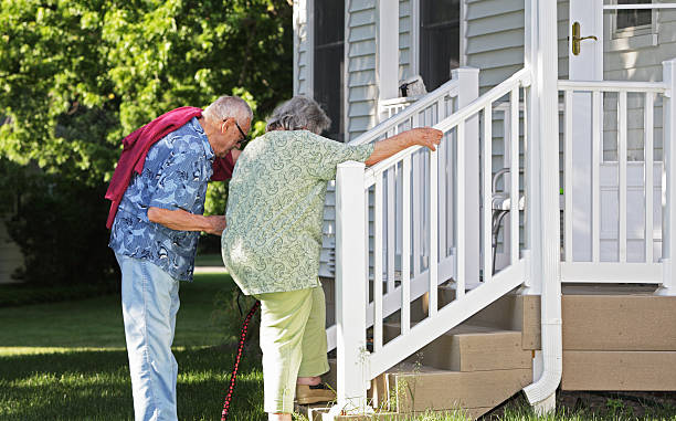 Senior Man Helping Wife Climb Stairs Elderly senior couple arriving home. He is helping her climb slowly up their back porch steps. caution step stock pictures, royalty-free photos & images