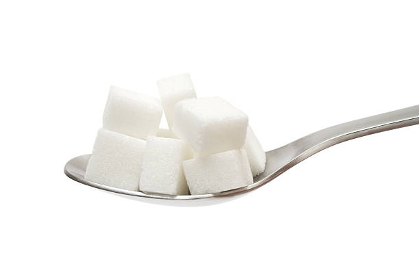 Sugar Cubes on Spoon Several sugar cubes on a silver spoon. Isolated on a white background. sugar cube stock pictures, royalty-free photos & images