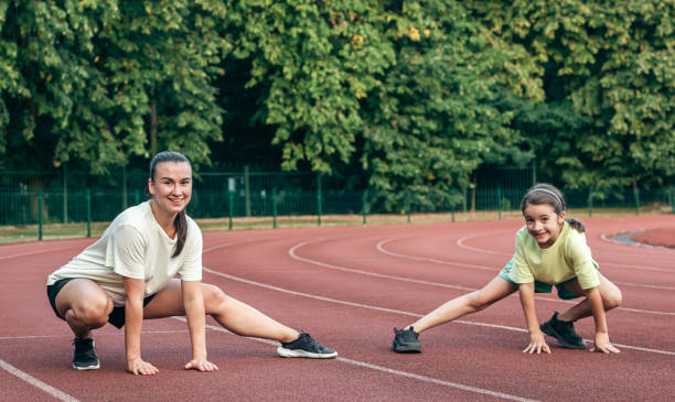 istock Mother and little daughter are doing exercise in the stadium. 1700247538