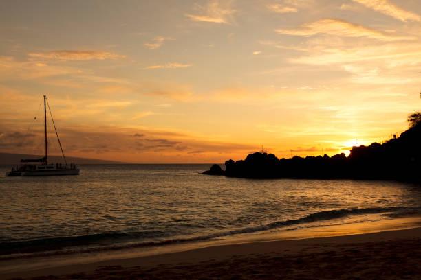 Sunset on Kaanapali Beach, Maui, Hawaii with Black Rock silhouetted by the setting sun. The island partially visible in the background is Molokai.