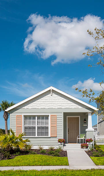 Front view of cottage house on sunny day Tidy little cottage with shutters, flowers, front yard and sidewalk. Affordable home; modest house. Space for copy. bungalow photos stock pictures, royalty-free photos & images