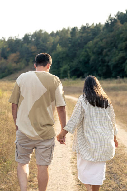 istock A man and a woman walk into a field holding hands. 1700269380