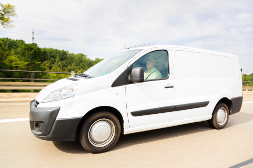 a white delivery van on a highway, motion blur. driver is model-released.