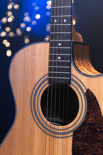 Close-up, acoustic guitar on a dark background with bokeh lights, concept for Christmas and winter holidays.