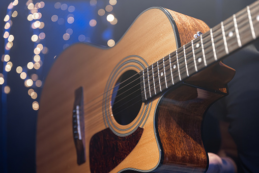 Close-up, acoustic guitar on a dark background with bokeh lights, concept for Christmas and winter holidays.