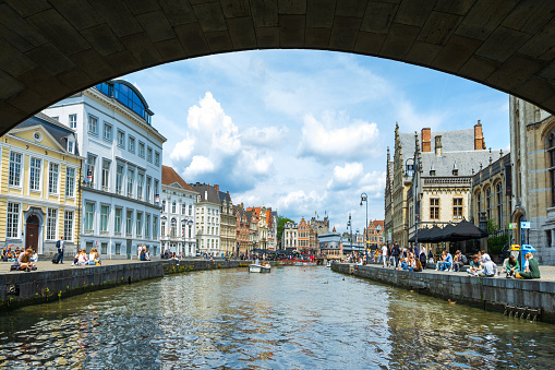Ghent, Belgium - June 30, 2023: General view of the historic and touristic Belgian city of Ghent from the river Leie, cafes and shops against medieval buildings in summer.
