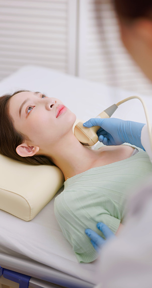 asian doctor using ultrasound scanner performing neck or thyroid examination for her patient - feminine health medical concept