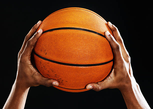istock Male hands hold up a basketball against black 170029331