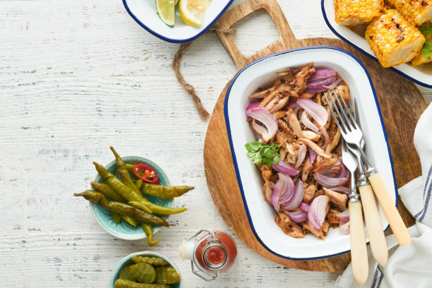 istock Pulled bbq chicken with baked onions on serving platter, bbq corn, pickles, chili peppers and buns for hot dogs and burgers, tomato sauce. Traditional American grilled summer bbq sandwiches dishes. 1700294000