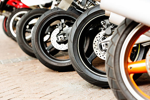 ряд разных motorbike wheels on brick поверхности - motorcycle in a row tire wheel стоковые фото и изображения