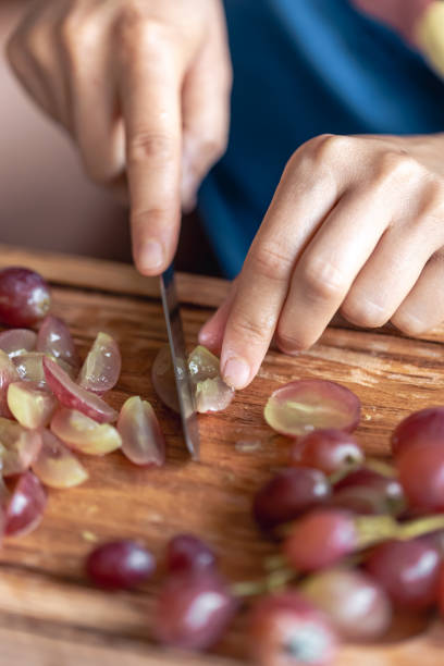 istock A woman cuts grapes on a cutting board. 1700296225