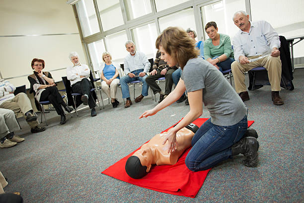 First Aid Training Course Group of mature and senior adults listening young female instructor explaining first aid training. cpr stock pictures, royalty-free photos & images
