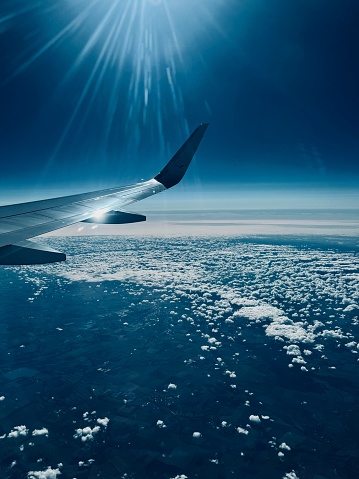 An aerial view of a commercial airplane wing flying over a bright blue sky