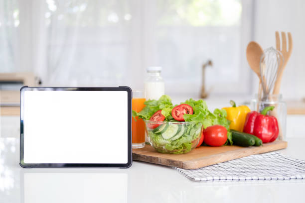 istock Digital tablet computer with mockup white screen on vegetarian healthy food vegetable background. Online grocery shopping delivery app ads concept, cook book diet plan nutrition recipes, close up view 1700313568