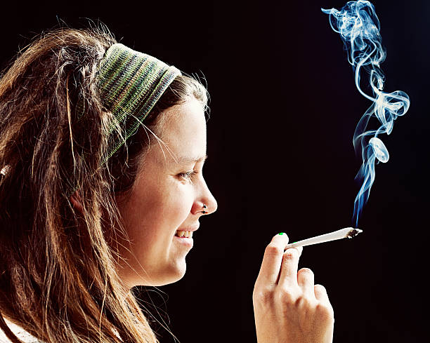 Smiling young rasta girl holds hand-rolled reefer