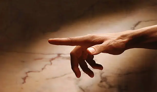 Close-up of a man's hand with extended index finger against a marble background.