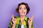Photo of young girl brown hair wear green checkered shirt crossed fingers look empty space prayer beg isolated on violet color background