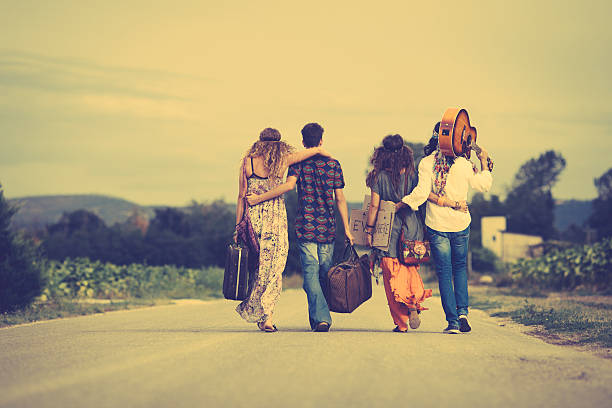 Group of hippie friends walk away Group of hippie friends walk away. Vintage style walking away into sunset with guitar stock pictures, royalty-free photos & images