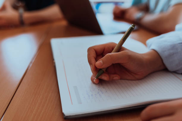 istock A female hand diligently records essential business ideas in a notebook while engaging in a discussion with colleagues about solving corporate challenges, portraying effective teamwork, communication, and strategic planning 1700334199