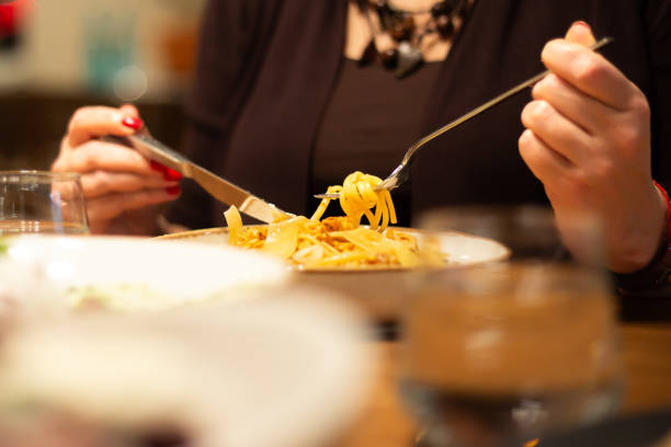 A lady is eating a spaghetti at fine-dining restaurant.